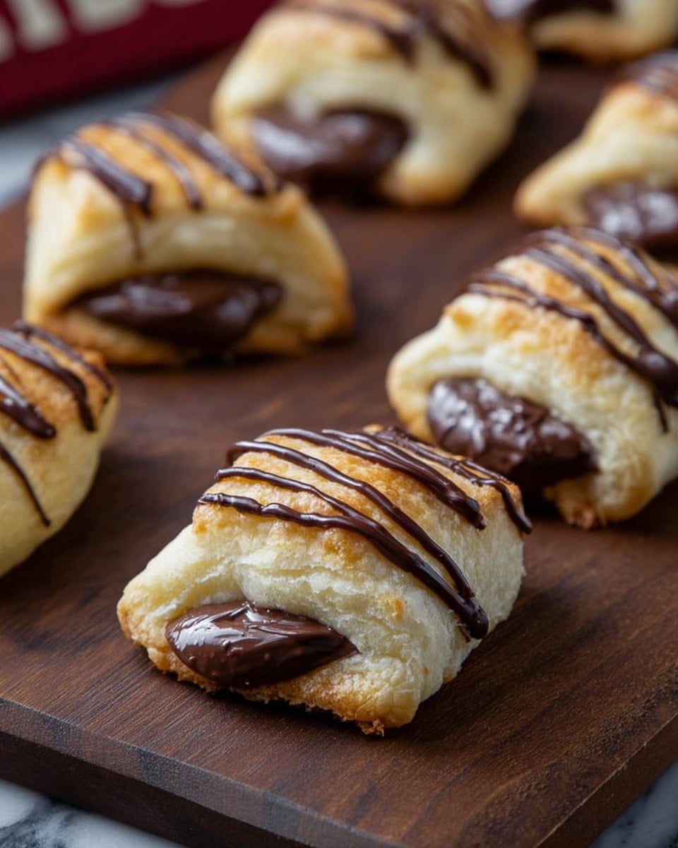 The image shows several small square pastries on a metal cooling rack over a white marbled surface. Each pastry has two layers: the bottom layer is thick, dark chocolate filling with a smooth texture visible at the edges, and the top layer is a light golden, soft dough that looks slightly puffed. Thin lines of dark chocolate drizzle are spread across the top of each square in a zigzag pattern, adding a glossy contrast to the matte dough. The edges of the pastries show some of the chocolate filling peeking out under the dough. The photo taken with an iphone --ar 4:5 --v 7