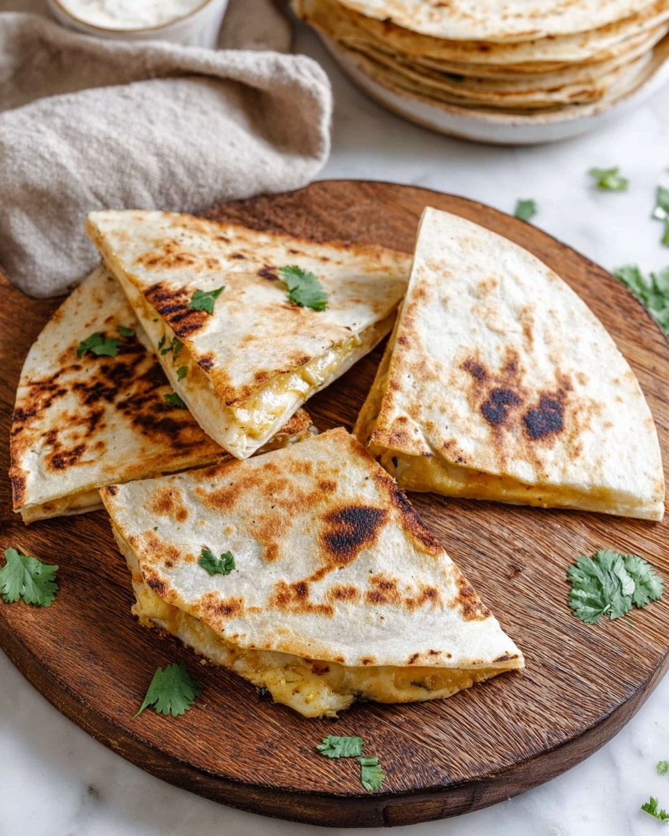 The image shows four triangular quesadilla slices arranged on a round wooden cutting board placed on a white marbled surface. Each quesadilla slice has a golden brown and slightly charred top layer with grill marks and spots, showcasing a crispy texture. The inside of the quesadilla is slightly visible, showing a creamy, light-yellow cheese filling. Small green cilantro leaves are scattered on top of the quesadilla pieces and around the board, adding a touch of fresh color. In the background, there is a stack of whole quesadillas with the same browned toasted top layer. A small white bowl with a textured light substance and a beige cloth napkin are partially visible near the edges of the frame. The scene is bright and clear. photo taken with an iphone --ar 4:5 --v 7