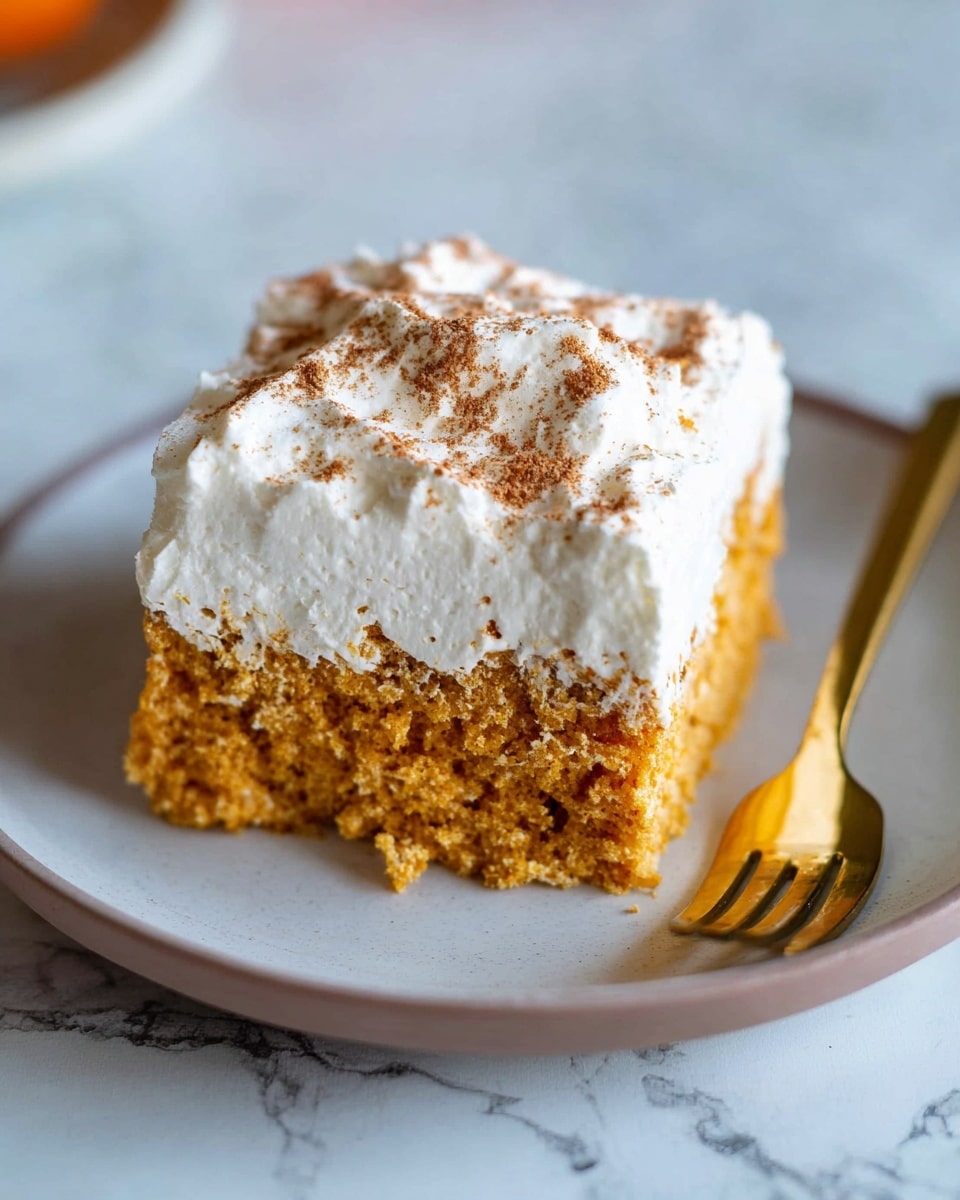 A close-up of a square piece of cake with two visible layers on a white plate, the bottom layer is light brown and moist with a soft texture, the top layer is thick white cream covered with a light dusting of cocoa powder, and a gold fork is placed next to the cake on the right side; the setting is on a white marbled surface. photo taken with an iphone --ar 4:5 --v 7