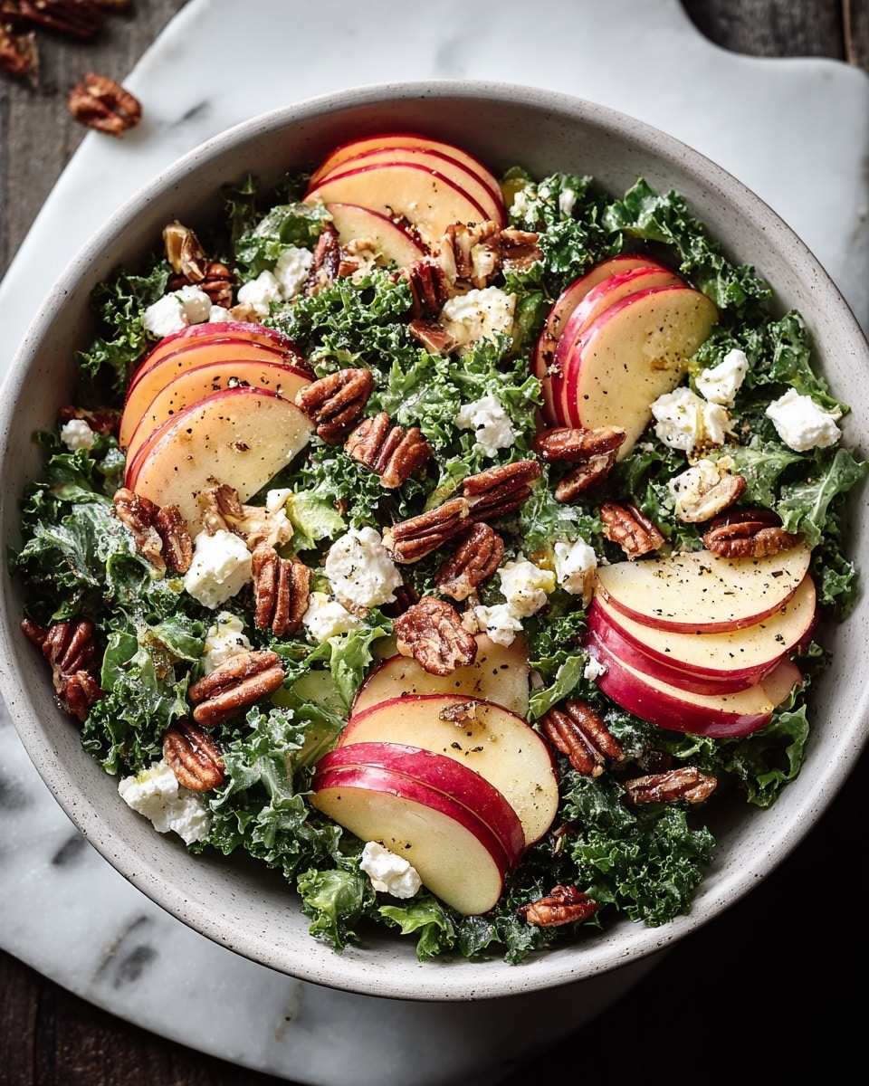A bowl filled with a fresh salad layered with dark green kale at the bottom, followed by thin slices of red and yellow apple spread evenly on top. The next layer includes small clusters of creamy white cheese crumbled across the salad, mixed with crunchy brown walnuts scattered around. The entire salad is lightly drizzled with olive oil and sprinkled with black pepper. The bowl is white with a subtle speckled texture on the outside, sitting on a white marbled surface. Photo taken with an iphone --ar 4:5 --v 7
