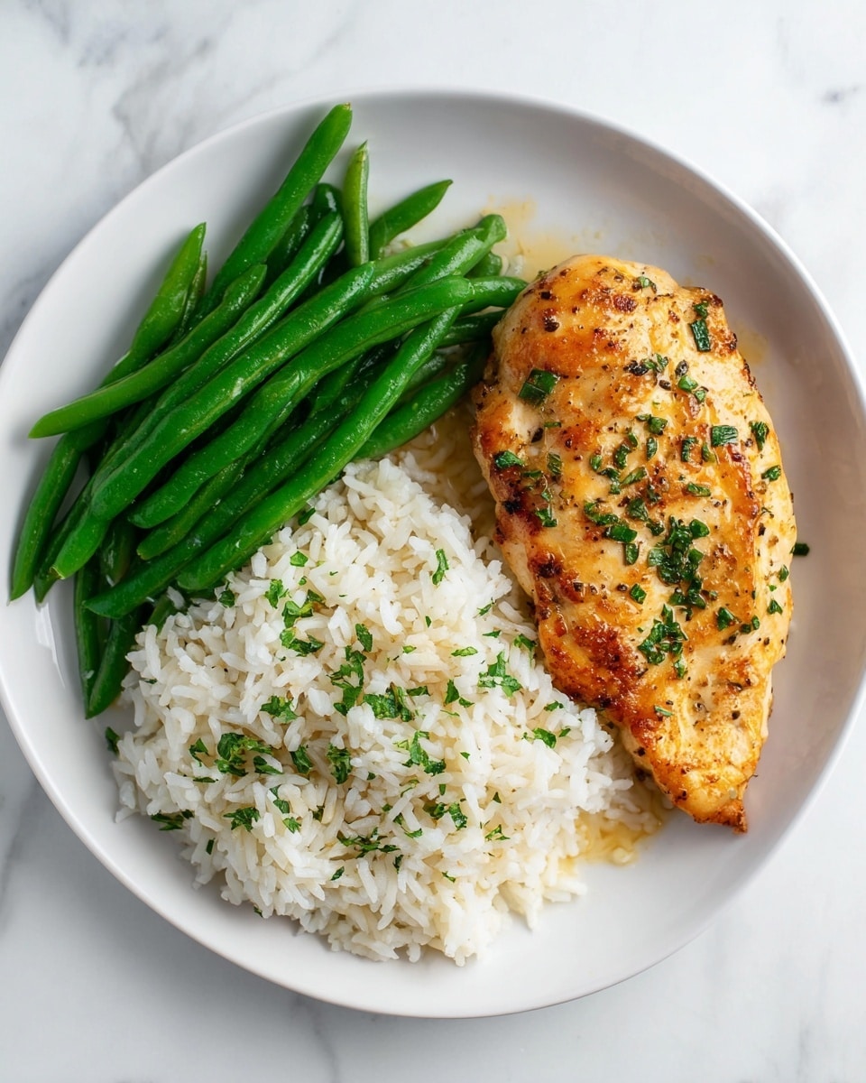 The image shows a white plate with three main parts: on the right, there is a single grilled chicken breast with a golden-brown crust and small green herb pieces sprinkled on top; on the left side, there is a neat pile of white rice garnished with green herbs and a little light sauce; above the rice, a cluster of vibrant green cooked green beans is placed side by side, looking fresh and slightly shiny. The plate is set on a white marbled surface. Photo taken with an iphone --ar 4:5 --v 7