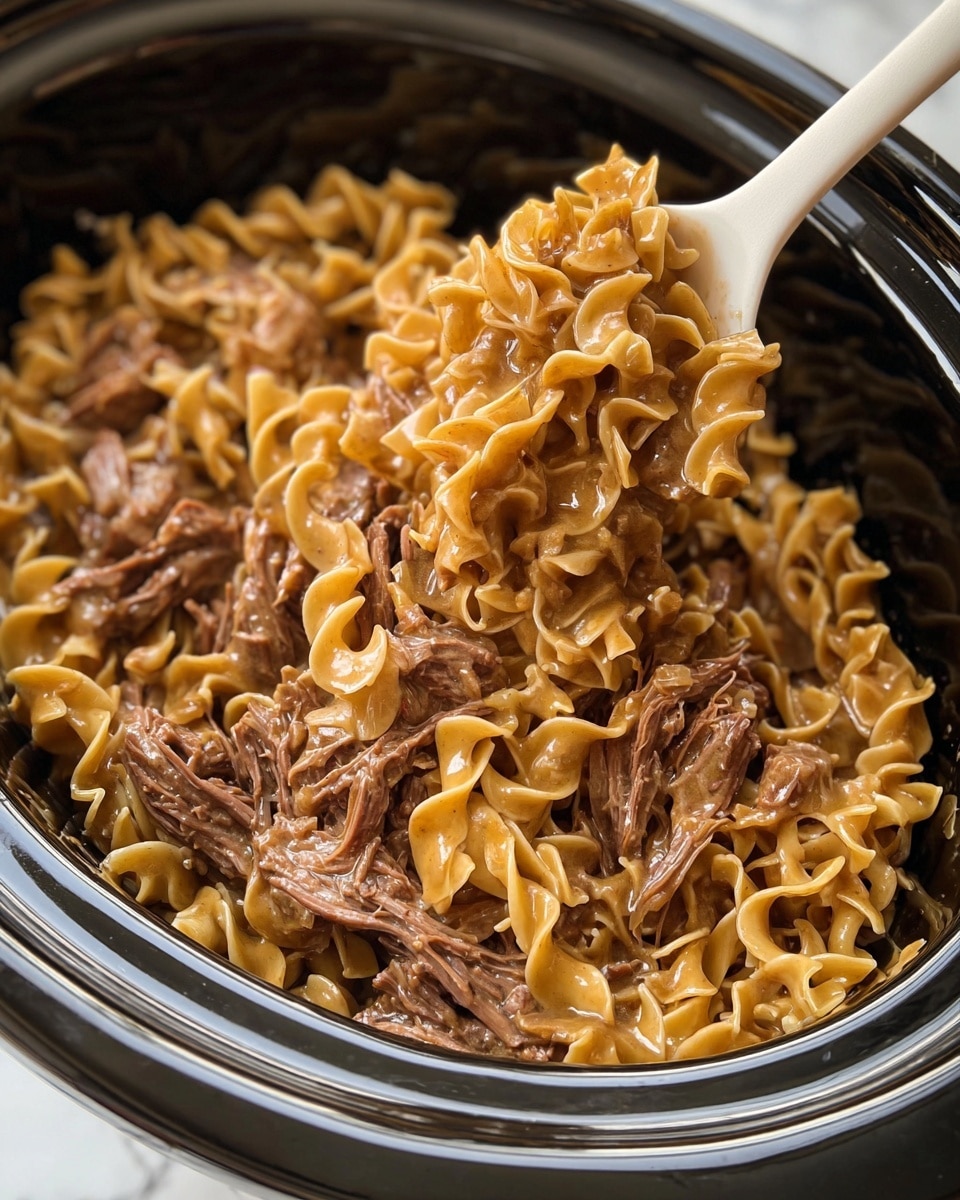 A close-up view of a large black slow cooker filled with cooked egg noodles mixed with shredded and chunked pieces of brown meat. The noodles are light tan, curly, and coated with a shiny brown sauce that glistens under the light. On top, a white spoon is scooping a portion of noodles and meat, showing a thick texture with tender meat fibers mixed in. The slow cooker is resting on a white marbled surface. photo taken with an iphone --ar 4:5 --v 7