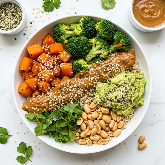 A bowl with four main layers sits on a white marbled surface. At the bottom, there is a layer of light brown grains. On top, from left to right, there are bright orange roasted cubed sweet potatoes with a slightly charred texture, steamed green broccoli florets, and a section of light beige peanuts. Over the middle of the bowl, there is a thick, shiny orange sauce with herbs sprinkled on top. Small white and black seeds and green leaves are scattered on the bowl and the surface around it. Two small bowls with sauces or toppings sit in the background. Photo taken with an iphone --ar 4:5 --v 7