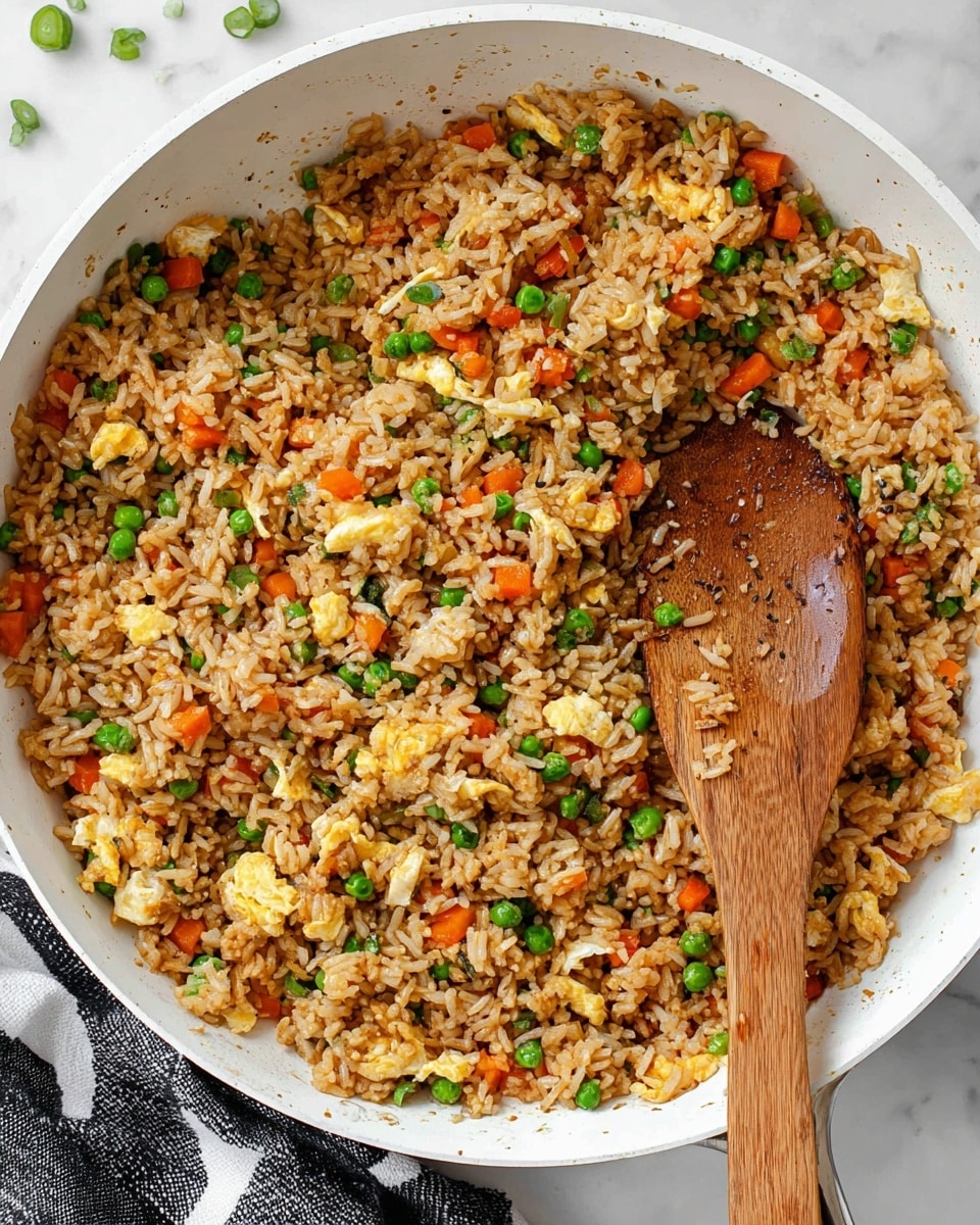 A white bowl is filled with a single layer of fried rice, showing mixed small pieces of scrambled egg in soft yellow, bright green peas, and small orange carrot cubes, all cooked evenly with light brown rice and dark specks of black pepper spread throughout. Two dark brown chopsticks rest on the right side of the bowl, partially touching the rice. The bowl sits on a white marbled surface with scattered green onion slices nearby and a small wooden bowl with chopped green onions in the upper right corner. photo taken with an iphone --ar 4:5 --v 7