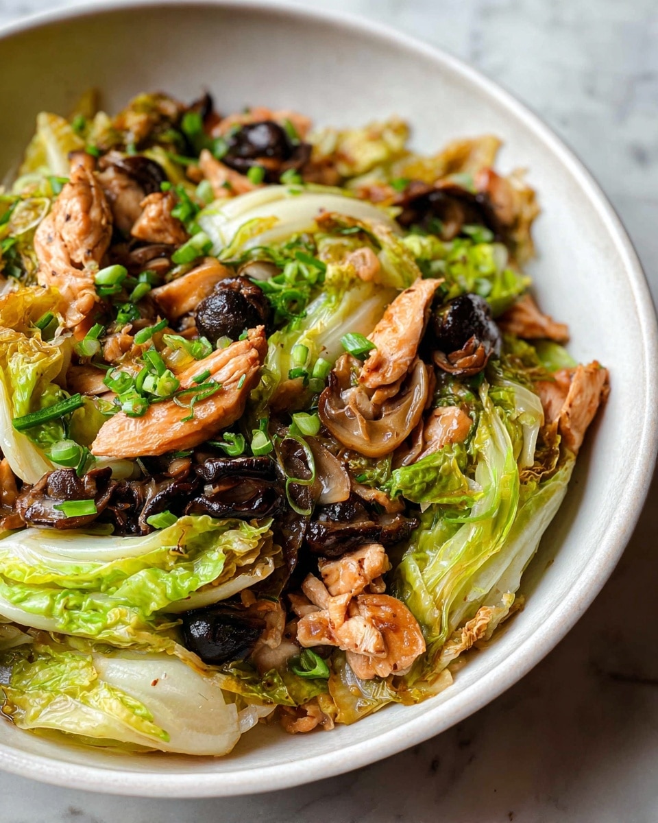 A white speckled bowl filled with a stir-fry dish showing three main layers: the bottom layer contains light green and slightly translucent cooked napa cabbage leaves, the middle layer has golden brown seared chicken pieces with a crispy texture, and the top layer is scattered with dark brown sliced mushrooms and bright green chopped scallions. A wooden spoon rests on the right side inside the bowl, slightly lifting some cabbage and mushrooms. The bowl is placed on a white marbled surface with a small round dish containing red chili flakes slightly visible at the top right corner and a soft pink cloth partially visible on the bottom left photo taken with an iphone --ar 4:5 --v 7
