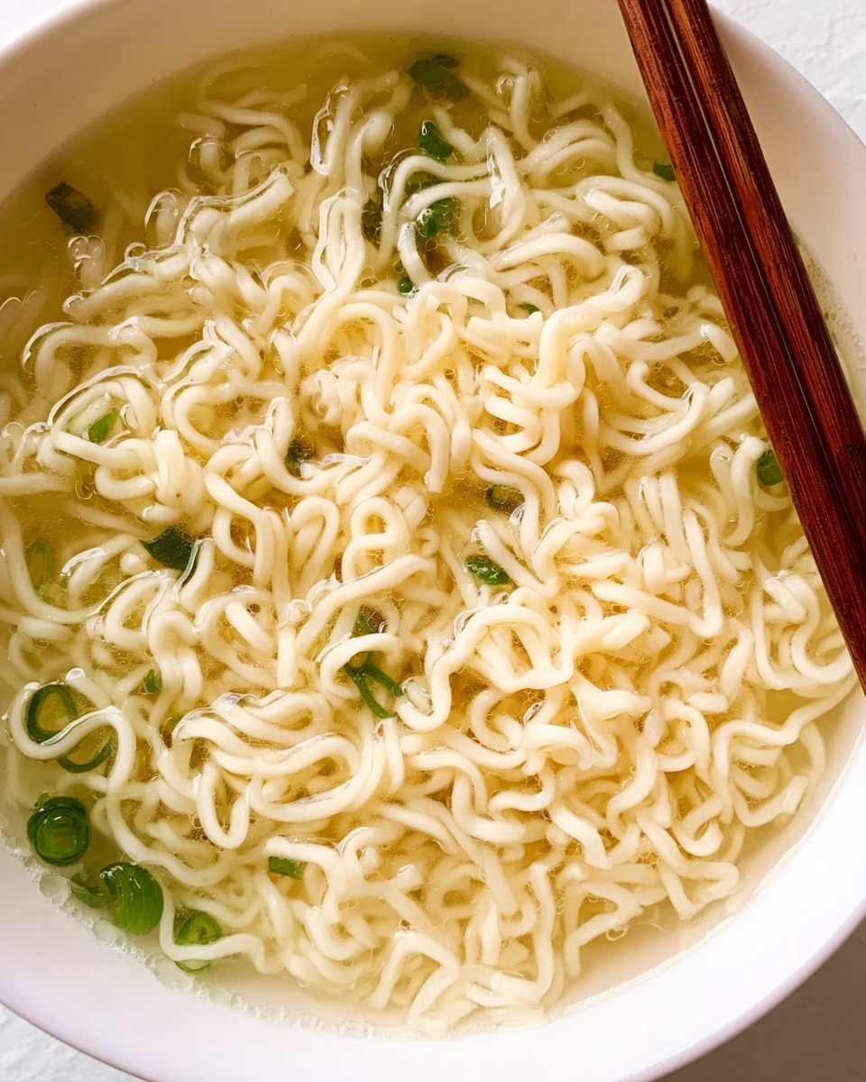 A clear glass jar is shown with its wooden lid leaning against it on a clean white marbled surface. Inside the jar, there is a layer of coarse yellowish powder mixed with green dried herbs, filling about one-third of the jar. In front of the jar, a wooden spoon lies flat, holding a small mound of the same yellow powder mixed with green herbs, slightly spilling onto the surface around it. The background is softly out of focus, maintaining the clean and minimal look. Photo taken with an iphone --ar 4:5 --v 7