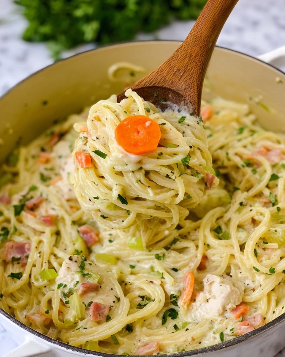 A close-up of a creamy soup in a shiny pot on a white marbled surface, showing thick yellow broth filled with pale yellow cooked noodles, orange carrot slices, light green celery pieces, and bits of white chicken. The soup is sprinkled with small green parsley flakes and black pepper. The pot handles and part of a striped white cloth are visible in the background. photo taken with an iphone --ar 4:5 --v 7