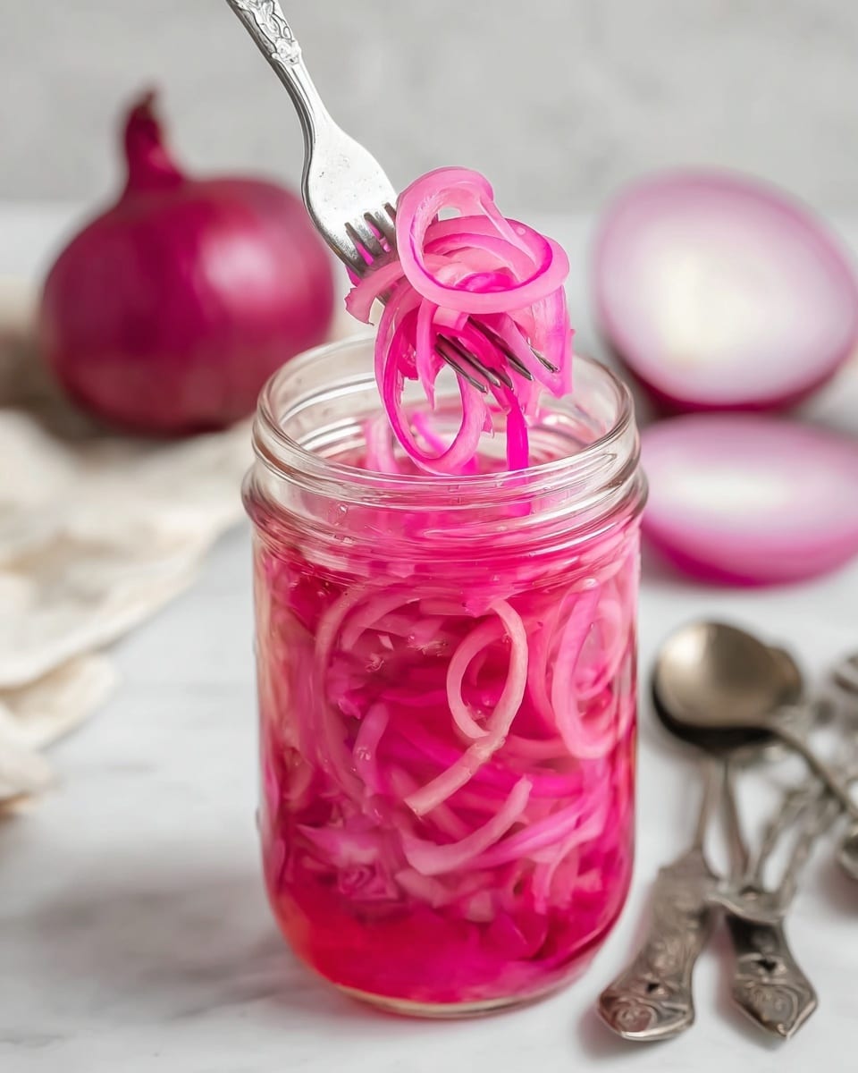 The image shows a clear glass jar filled with bright pink pickled onion slices packed tightly inside a light pink liquid. The jar is open with thin, curly onion slices being lifted out by a silver fork from the top center, showing vibrant translucent layers. In the blurred background, there is a whole red onion and white onion halves resting on a white marbled surface. Some measuring spoons are loosely arranged in the bottom right corner. The overall scene has soft natural light and clean colors. photo taken with an iphone --ar 4:5 --v 7