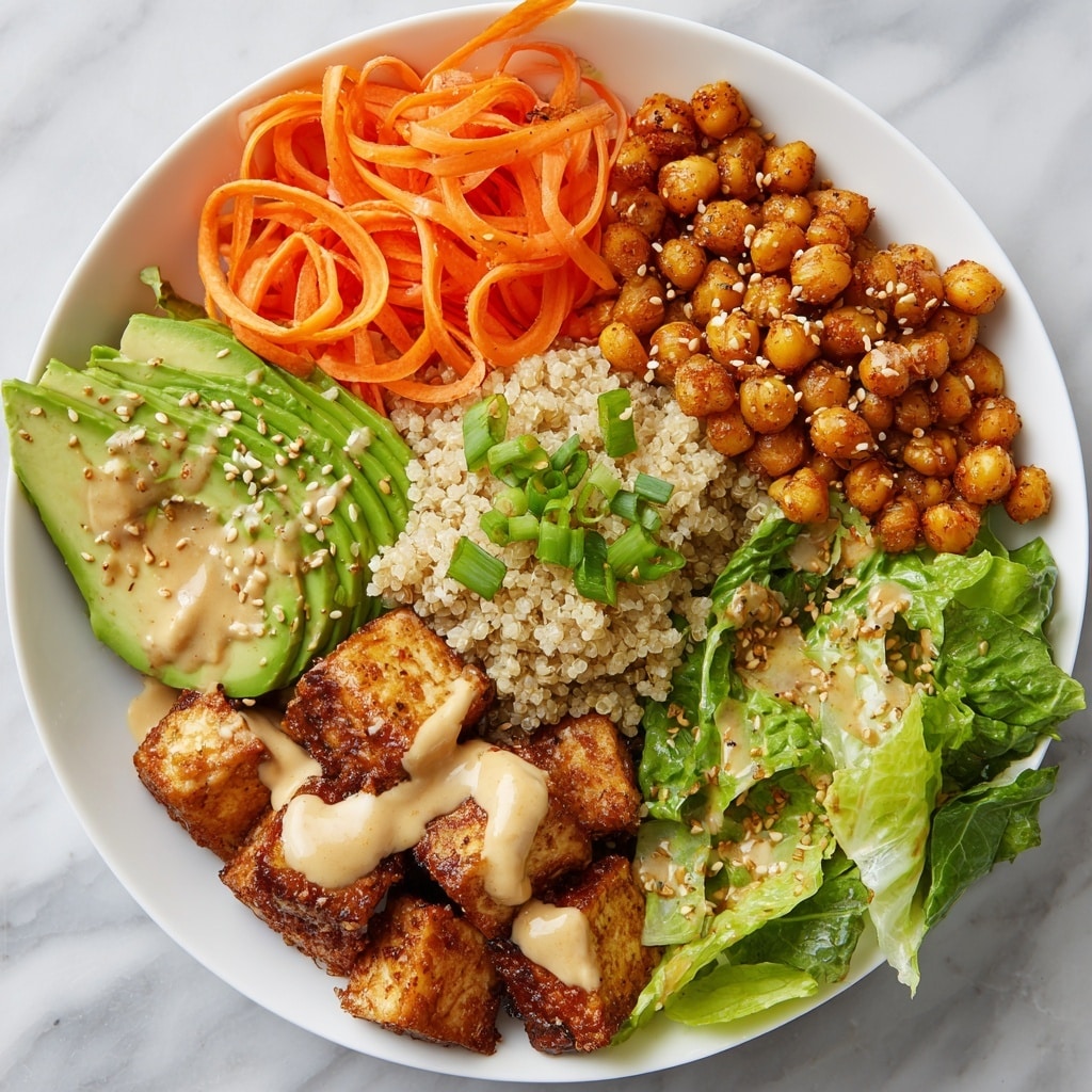 A white bowl filled with several colorful layers of food is presented. In the bottom left part of the bowl, there are dark brown crispy tofu cubes sprinkled with white sesame seeds and green chopped scallions. Next to the tofu, in the lower right section, is a generous portion of cooked quinoa with small green bits and green scallions on top. Above the quinoa, thin bright orange shredded carrots are piled high with a sprinkling of black and white sesame seeds. In the top left part of the bowl, crispy golden roasted chickpeas sit behind dark green cooked kale drizzled with creamy beige sauce. In the center, fresh bright green avocado slices fan out with more of the same beige sauce and sprinkled sesame seeds on top. The bowl is placed on a white marbled surface with a silver fork nearby. photo taken with an iphone --ar 4:5 --v 7