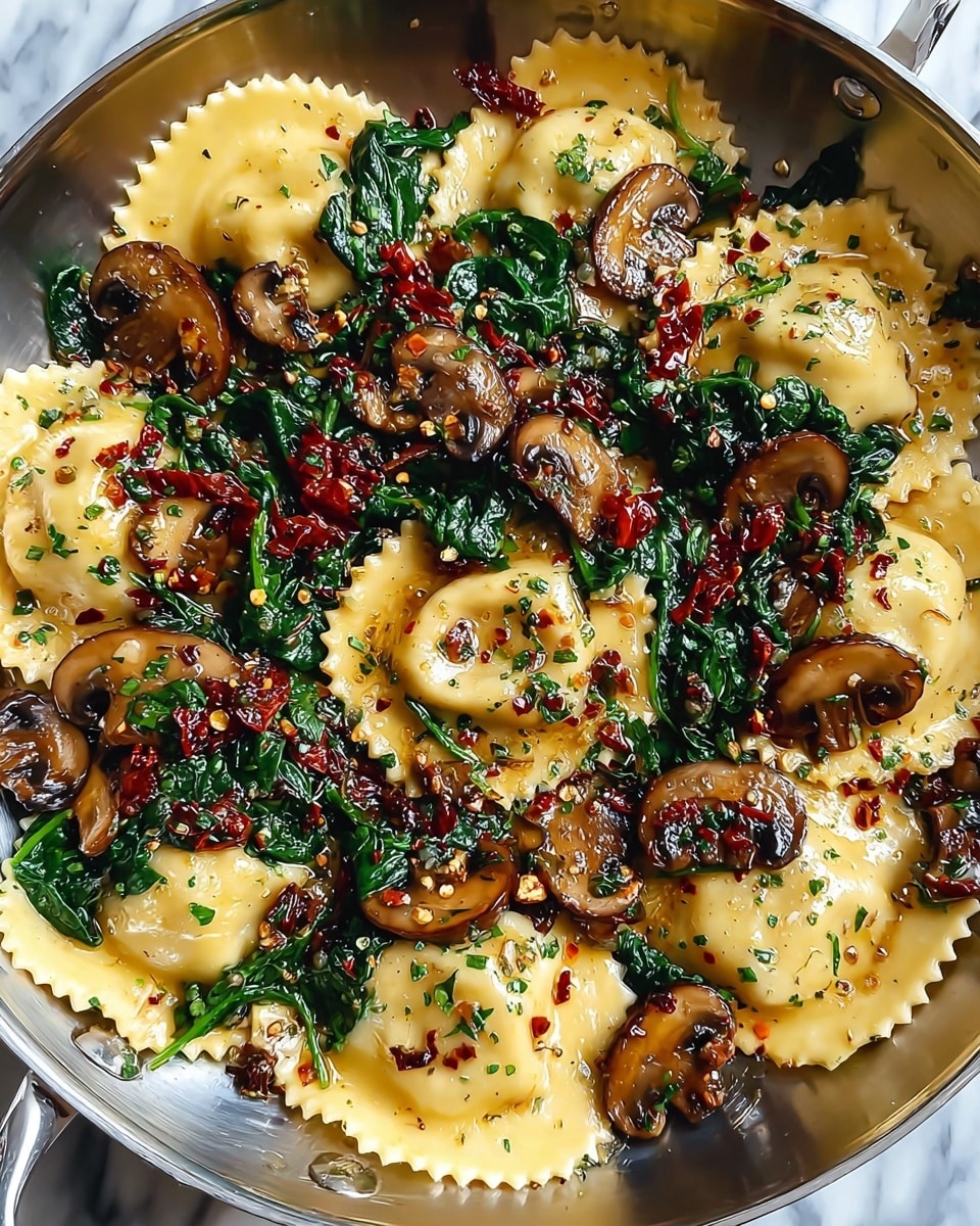 The image shows a close-up of a pan full of ravioli with three main layers: the bottom layer consists of light yellow ravioli with scalloped edges, arranged evenly throughout the pan; on top of that, there are glossy sautéed brown mushroom slices with a slightly crispy edge scattered in between the ravioli; the top layer features vibrant green spinach leaves mixed with small pieces of dark red sun-dried tomatoes and sprinkled with finely chopped herbs and crushed red pepper flakes, all glistening with a light coating of oil. The pan is silver, and the background is a white marbled texture. photo taken with an iphone --ar 4:5 --v 7