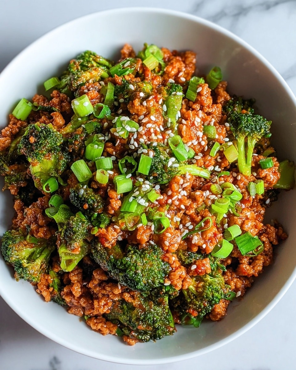 A bowl of cooked white rice forms the bottom layer, topped with a thick mix of bright green broccoli florets and light brown pieces of ground meat coated in a shiny reddish-brown sauce. Small chopped green onions are scattered on top, along with tiny white sesame seeds. The bowl is white and sits on a white marbled surface, enhancing the vibrant colors of the food. photo taken with an iphone --ar 4:5 --v 7