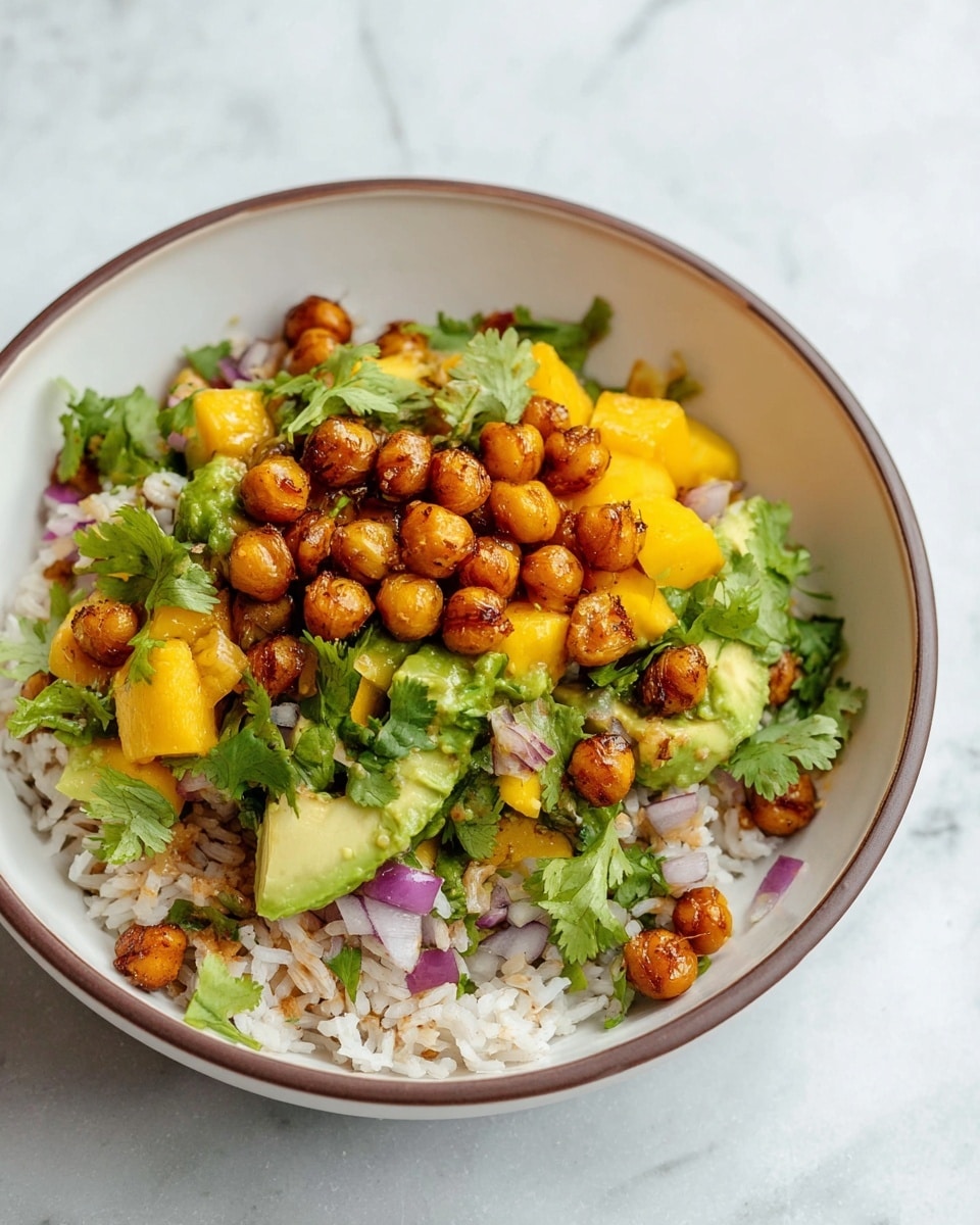 This dish is served in a white bowl with a thin brown rim, placed on a white marbled texture. It has three visible layers: the bottom layer is white rice mixed with tiny bits of a light brown ingredient, the middle layer is a mix of bright yellow mango chunks, light green avocado pieces, and small bits of chopped red onion with fresh green cilantro leaves scattered throughout, and the top layer consists of golden-brown roasted chickpeas adding a crispy texture. The dish looks fresh, colorful, and vibrant with a mix of soft and crunchy textures. photo taken with an iphone --ar 4:5 --v 7