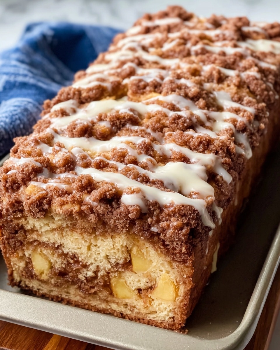 A rustic bread pudding is shown in a small rectangular metal baking pan filled with chunky pieces of golden and brown baked bread layered closely together, topped with a thick drizzle of creamy white sauce that spills over the sides of the pan onto a wooden board beneath. The bread pieces appear crunchy and textured, with some darker crisp edges and sugar coating. In the background, a blue and white checkered cloth is slightly out of focus, adding a cozy feel. The scene is set on a white marbled surface. photo taken with an iphone --ar 4:5 --v 7